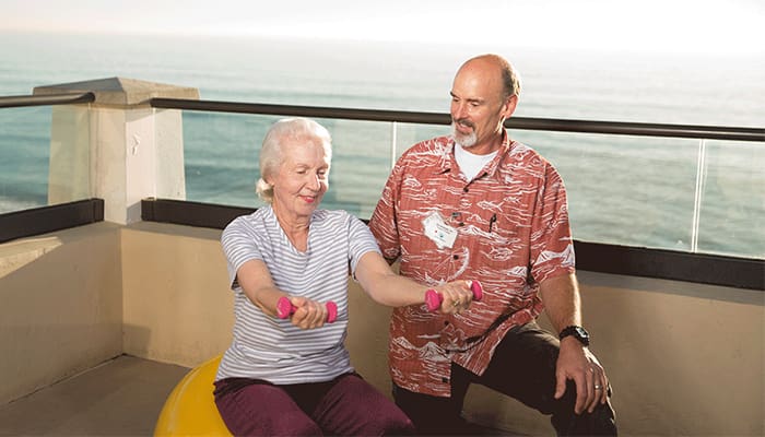 Carlsbad by the Sea staff member helping senior resident with weight training exercises