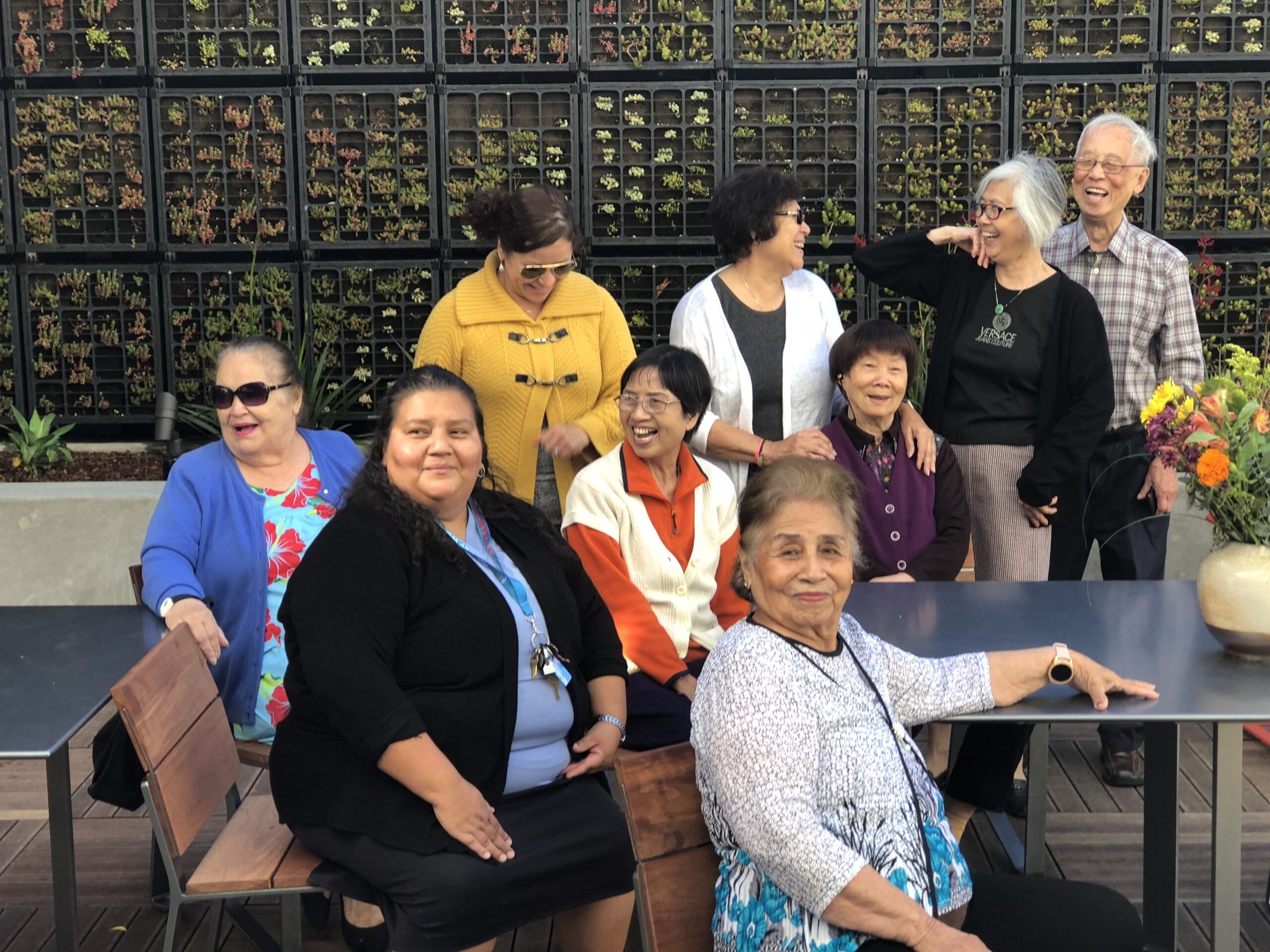 A group of residents gather in front of a living wall