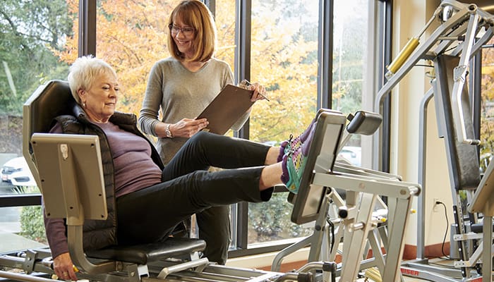 Spring Lake Village resident in the Fitness Center with a staff person