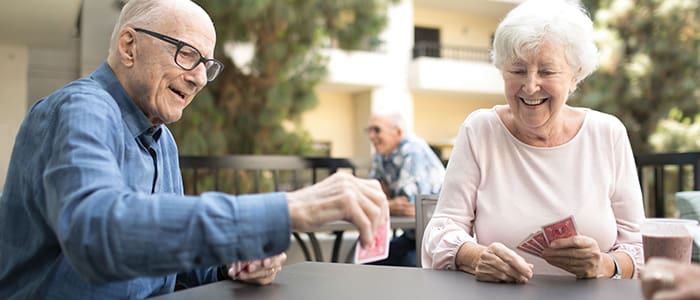 Smiling couple playing cards at Villa Gardens