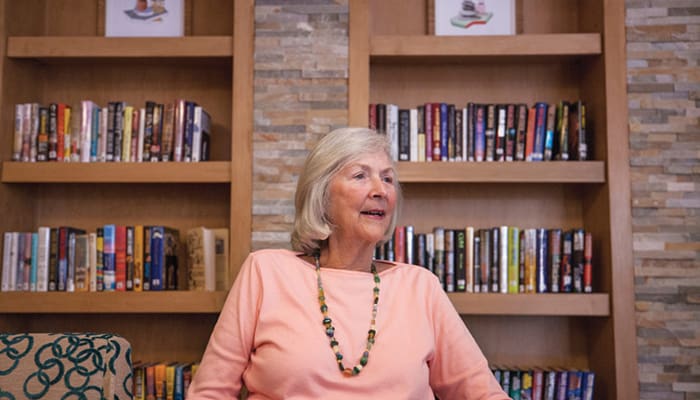 Portrait of a woman sitting in front of bookshelves at a library