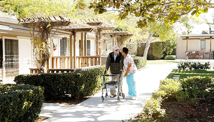 Staff member at Wesley Palms helping a senior resident walk outdoors