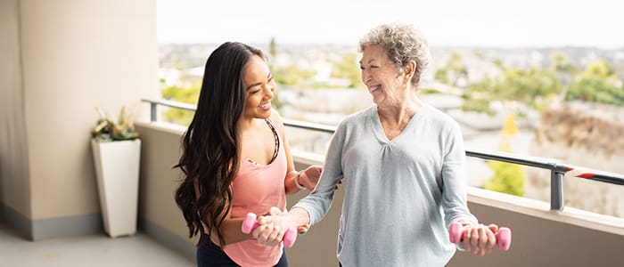 Woman helping senior resident with weight training at Wesley Palms